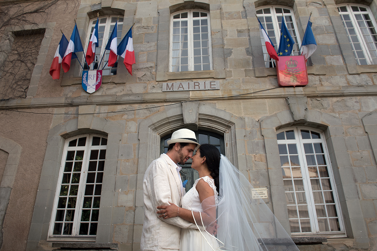 Un couple de mariés se regardent tendrement devant la mairie de Montréal dans l'Aude.