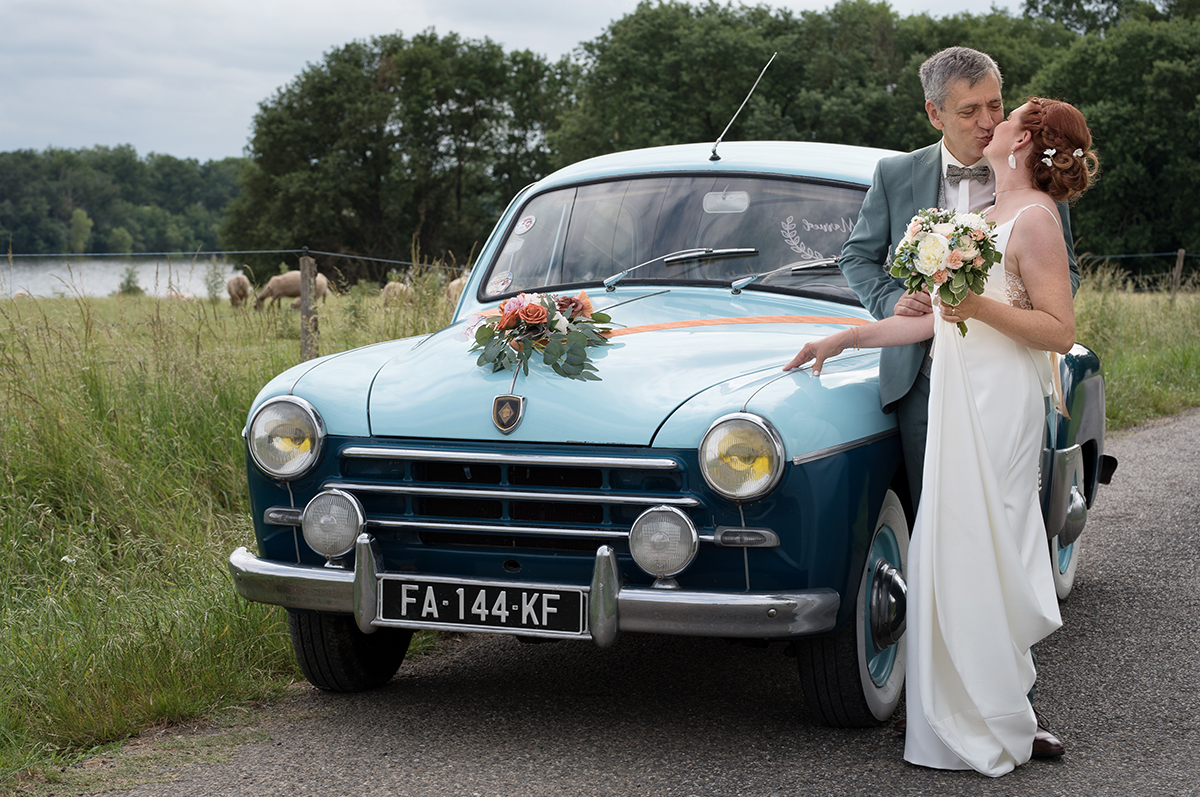 le couple de mariés s'embrase à coté de leur voiture vintage