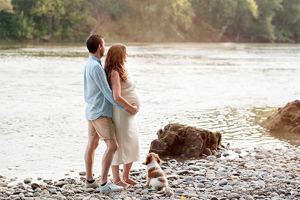 Le couple en attente de bébé devant la Garonne Le couple de futurs parents, en attente de bébé, regardent la Garonne à Blagnac avec leur petit chien à leurs pieds